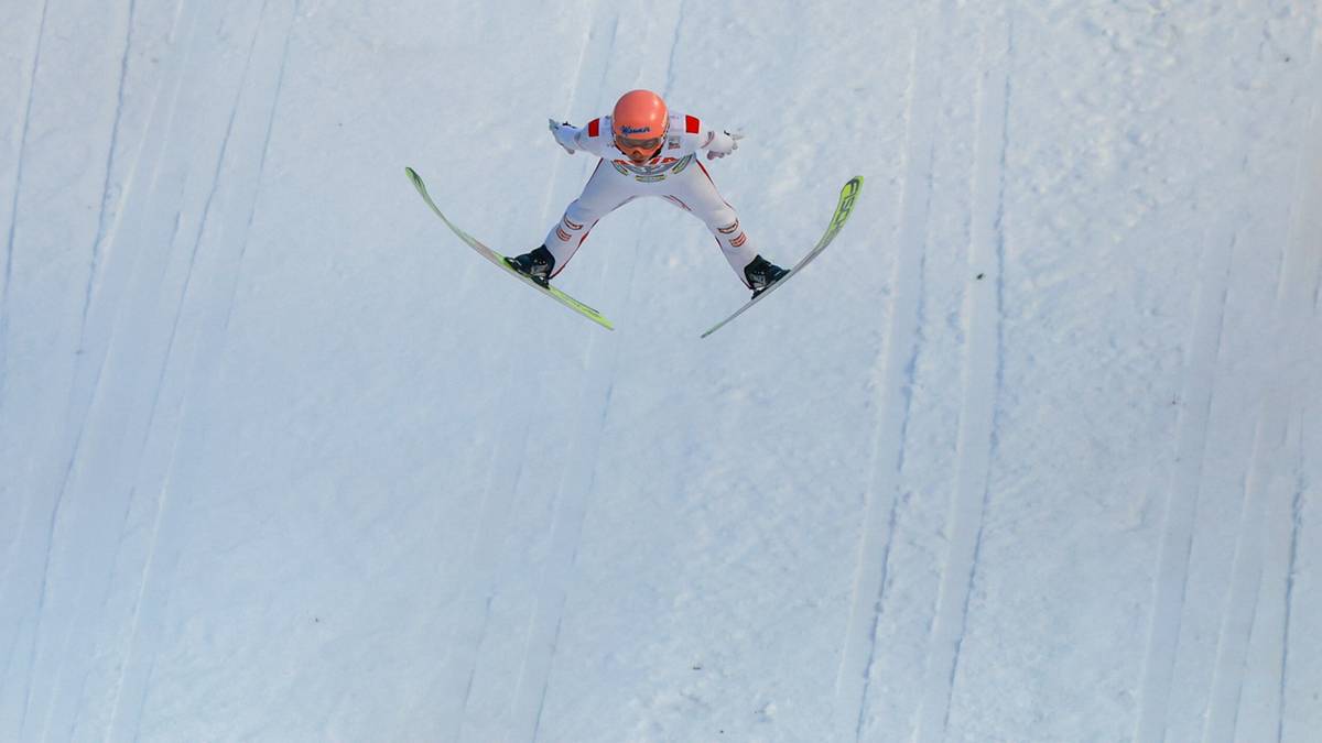 Skoczek narciarski w powietrzu podczas zawod&oacute;w.