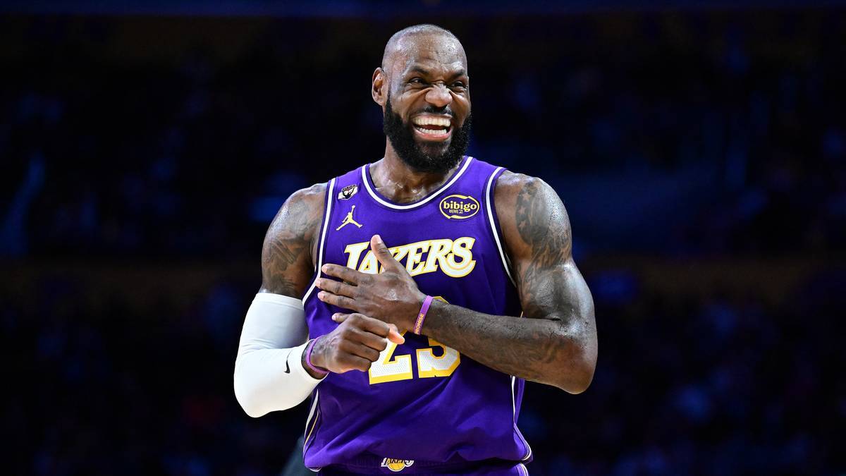 LeBron James w fioletowej koszulce Lakers z numerem 23, uśmiecha się i trzyma ręce na piersi.