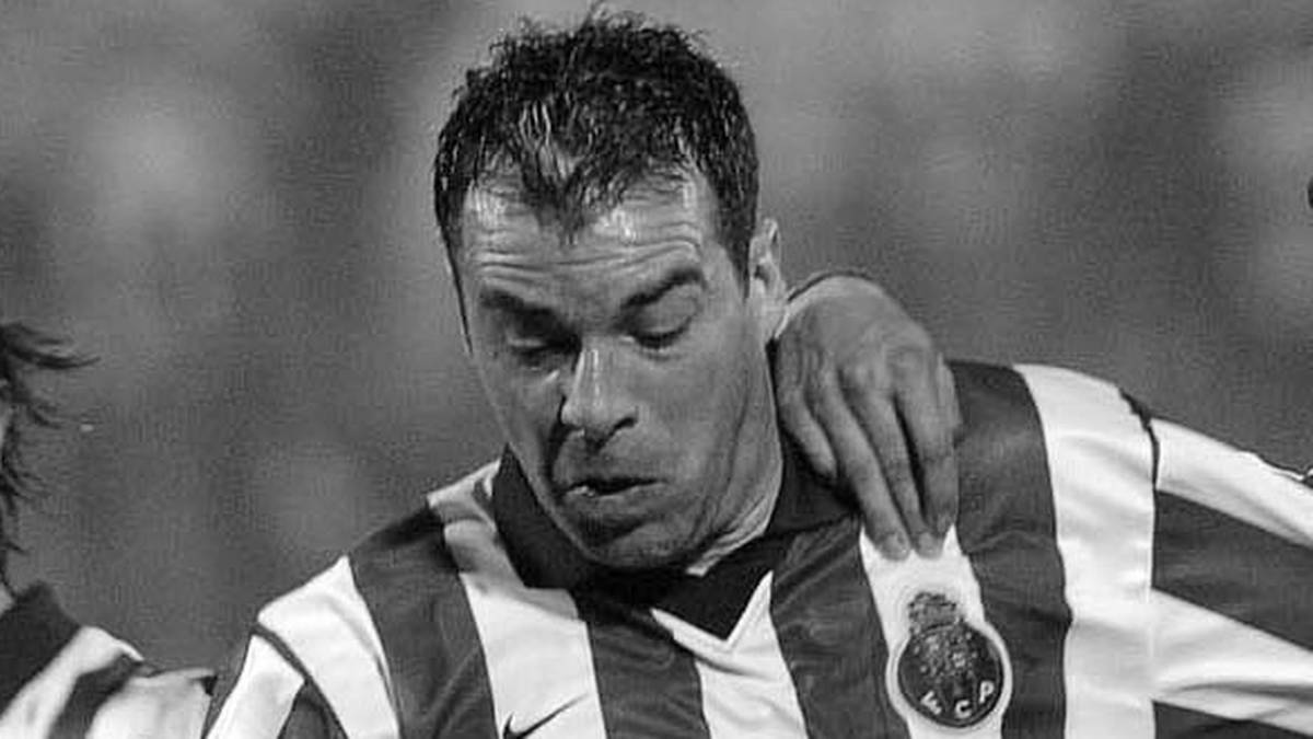 Czarno-białe zdjęcie mężczyzny w stroju piłkarskim, patrzącego w dół z zamkniętymi oczami, z dłonią innego zawodnika na ramieniu.