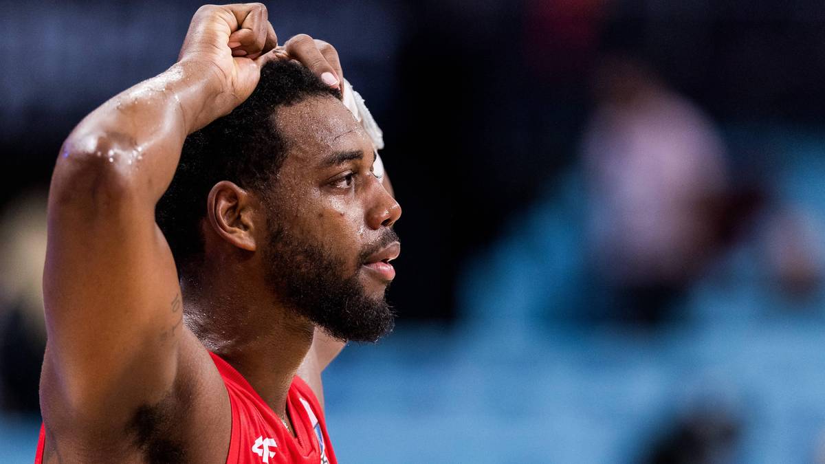 Mężczyzna w stroju sportowym, opierający dłonie na głowie, z widoczną opaską na czole.