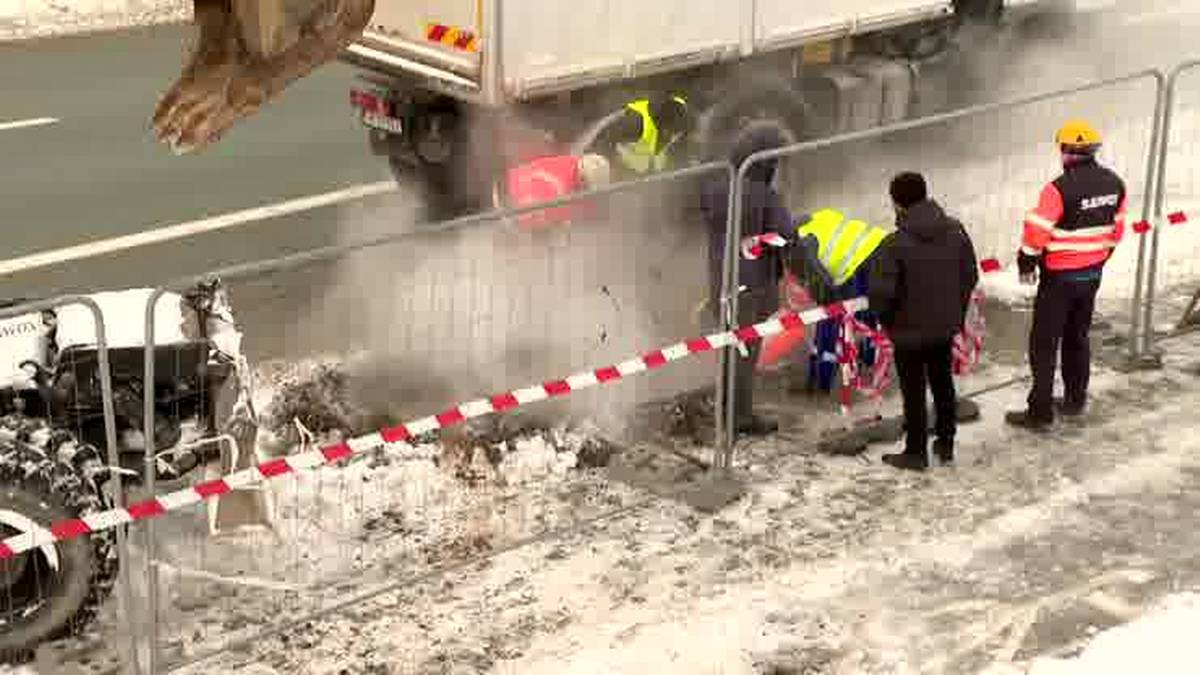 Awaria sieci ciepłowniczej, robotnicy zabezpieczają teren taśmą ostrzegawczą.