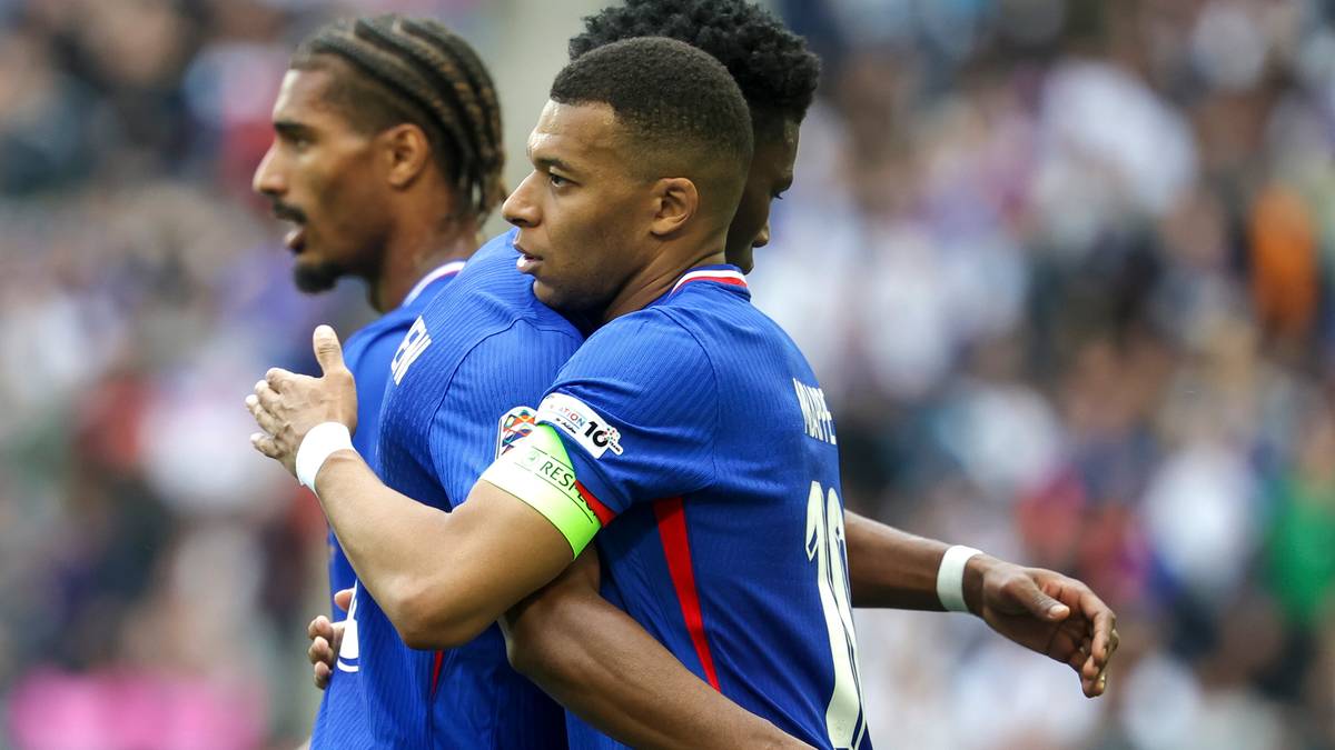 Dwóch piłkarzy reprezentacji Francji w niebieskich strojach podczas meczu, obejmują się nawzajem.