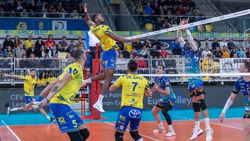 Siatkarze podczas meczu, jeden z nich wyskakuje do ataku nad siatką.