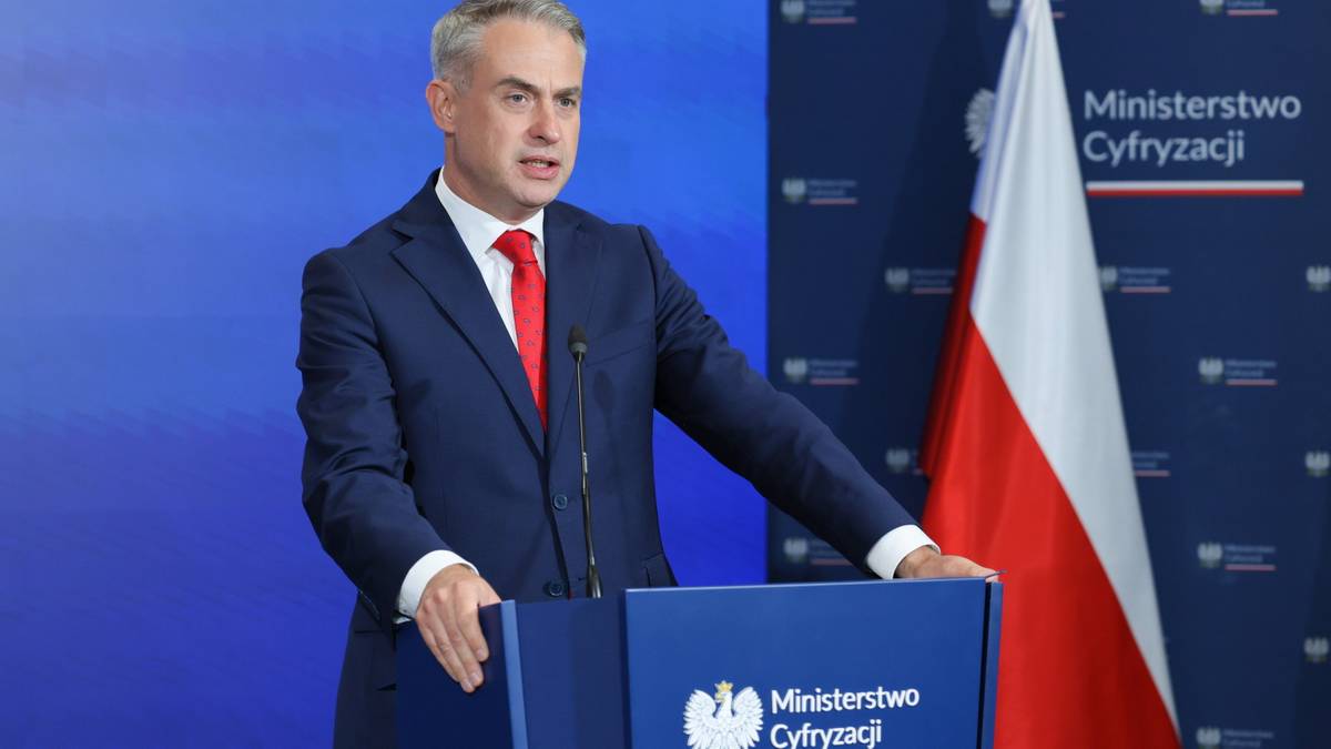 Mężczyzna w garniturze przemawia za mównicą Ministerstwa Cyfryzacji na tle polskiej flagi.