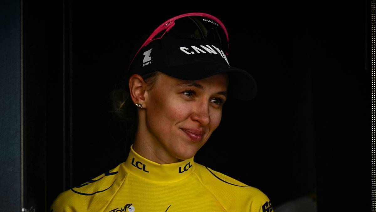 Zbliżenie na twarz młodej kobiety, rowerzystki, ubranej w żółtą koszulkę i czarną czapkę z daszkiem z widocznym logo. Kobieta uśmiecha się lekko.