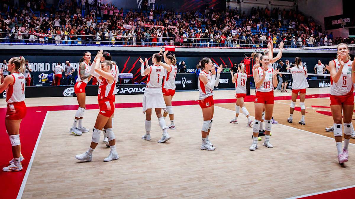 Grupa polskich siatkarek w czerwonych strojach, z uniesionymi rękami w geście radości lub gratulacji, stoi na parkiecie hali sportowej podczas meczu.