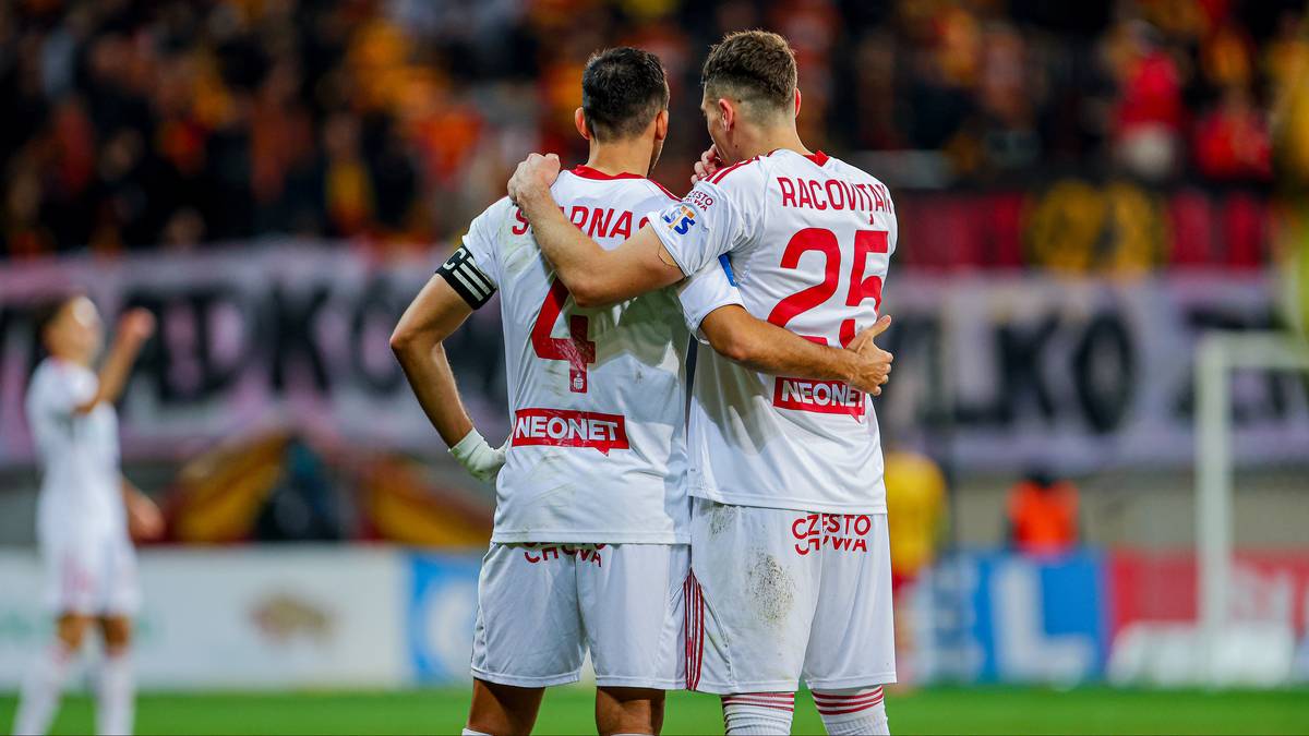 Dwóch piłkarzy Sparty Praga w białych strojach meczowych przytulających się na boisku.