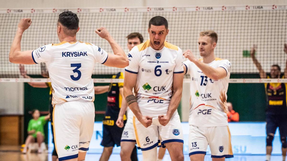 Siatkarze w białych koszulkach świętują zwycięstwo przy siatce.