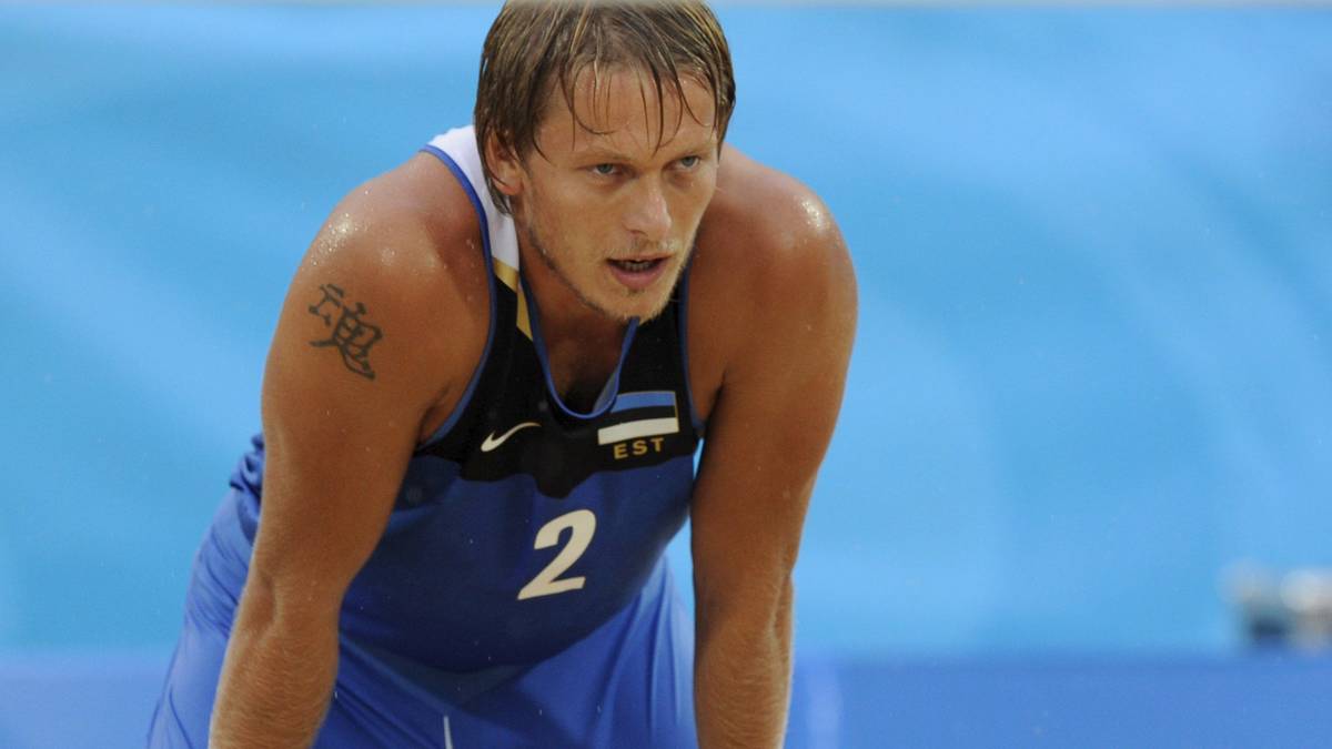 Sportowiec w niebieskiej koszulce z numerem 2 pochyla się z rękami na kolanach.