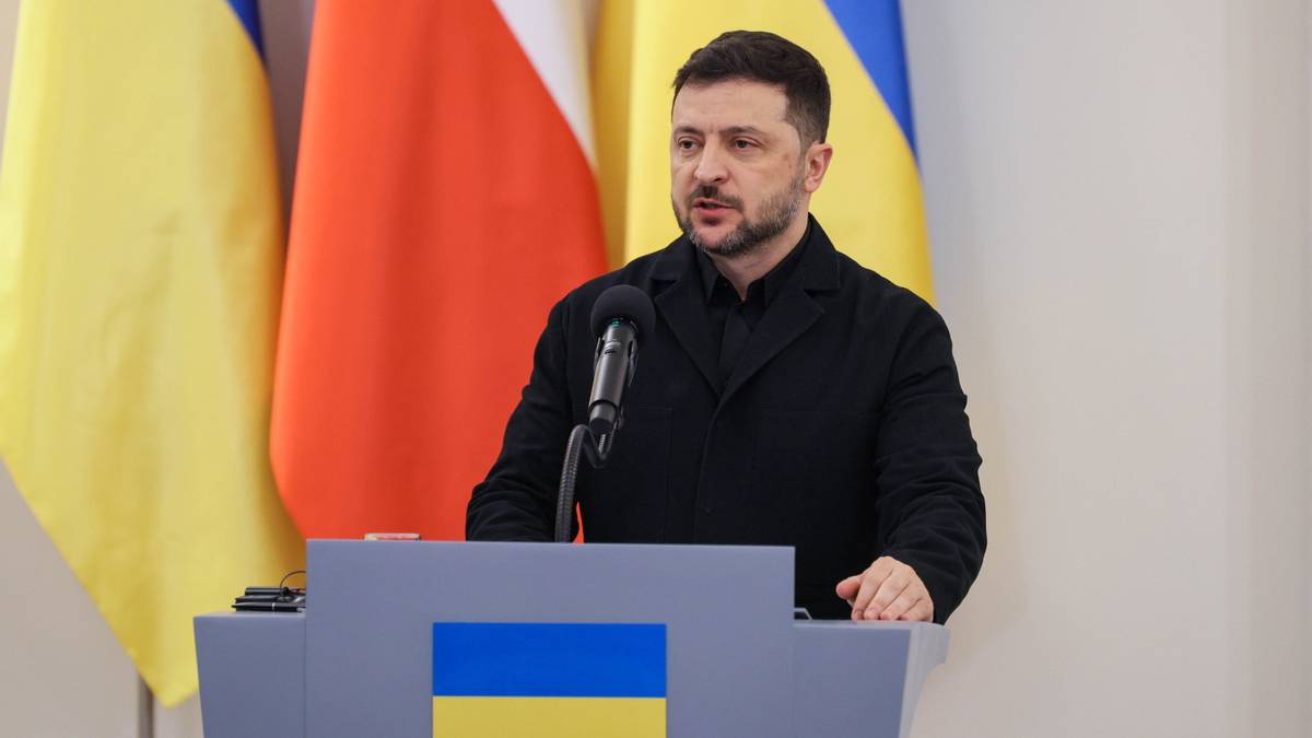 Wołodymyr Zełenski przemawia za m&oacute;wnicą, za nim flagi Polski i Ukrainy.