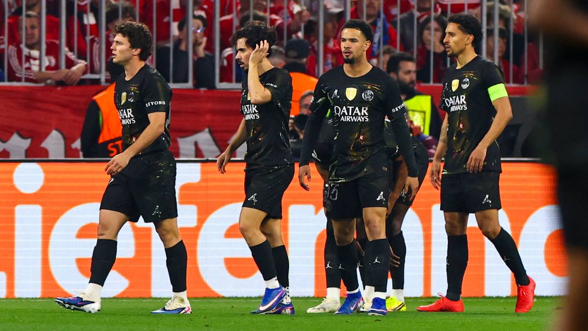 Piłkarze Paris Saint-Germain w czarnych strojach świętują zdobycie bramki na tle kibic&oacute;w Bayernu Monachium.