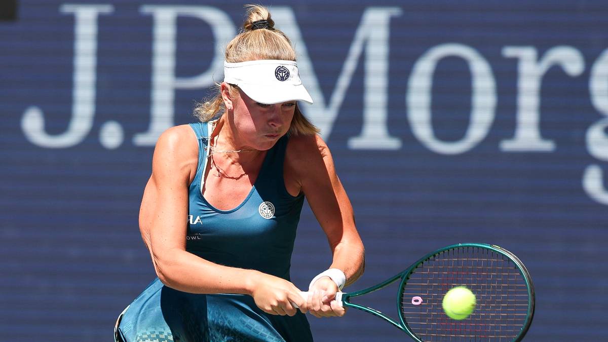 Tenisistka w niebieskim stroju, z czarną opaską na głowie, w trakcie meczu odbija piłkę rakietą.