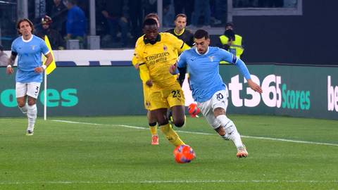 Piłkarz w żółtej koszulce z numerem 23 próbuje odebrać piłkę piłkarzowi w niebieskiej koszulce podczas meczu piłkarskiego.