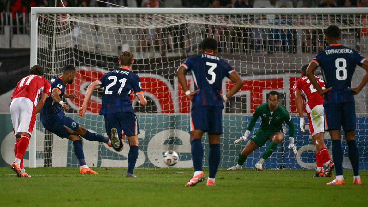 Piłkarze w niebieskich strojach w akcji podczas meczu piłki nożnej. Jeden z zawodników strzela bramkę.