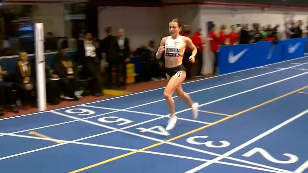 Zawodniczka biegnąca po niebieskim torze lekkoatletycznym.