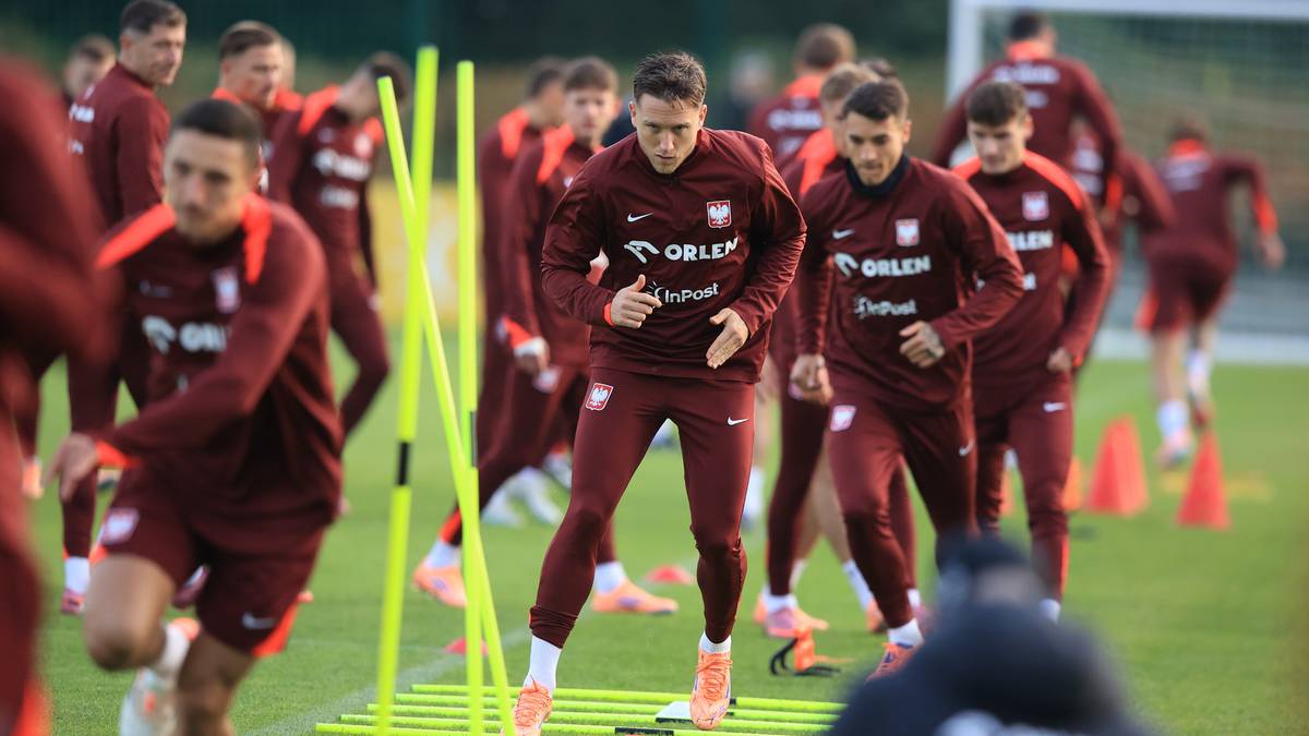 Piłkarze reprezentacji Polski w bordowych strojach ćwiczą na boisku z pachołkami.