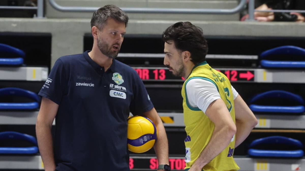 Trener siatkówki rozmawia z zawodnikiem.