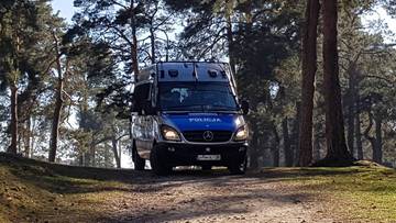 Samoch&oacute;d policyjny na leśnej drodze.