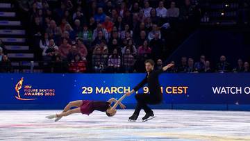 Para łyżwiarzy figurowych podczas zawodów, kobieta leży na lodzie, mężczyzna klęczy obok niej.