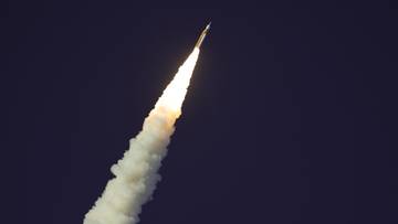 Rakieta SLS wznosząca się w g&oacute;rę, pozostawiająca za sobą gęsty biały dym.