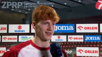 Młody mężczyzna z rudymi włosami udziela wywiadu przed bandami reklamowymi.