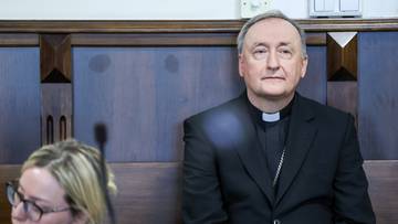 Biskup Andrzej Jeż siedzi w sali sądowej.