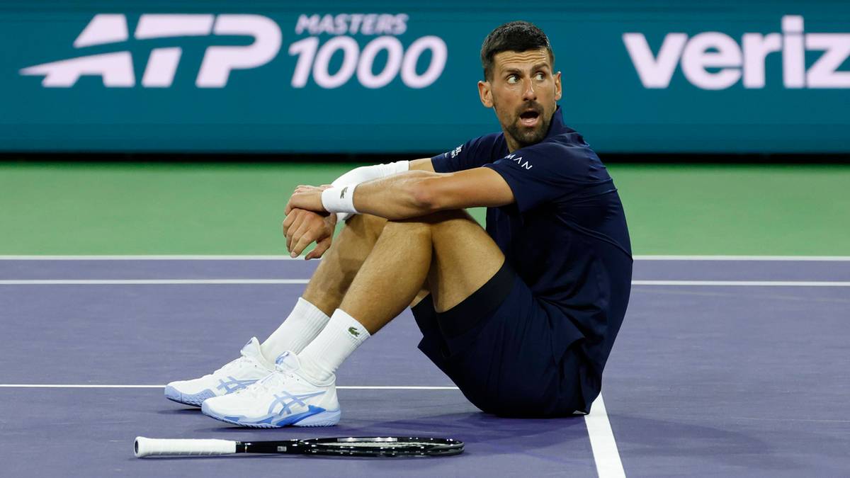 Novak Djoković siedzący na korcie tenisowym.