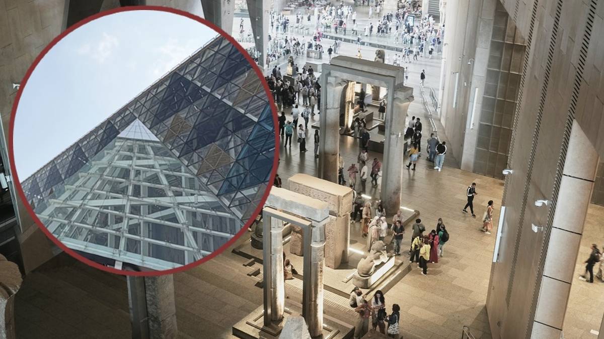Wnętrze Wielkiego Muzeum Egipskiego w Gizie z kolumnami, posągami i zwiedzającymi, z widocznym fragmentem szklanego dachu w rogu.