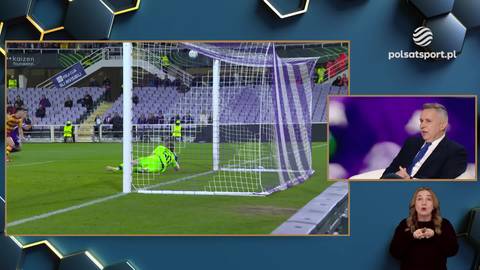 Bramkarz w zielonym stroju leży na ziemi po tym, jak piłka wpadła do bramki. Obok widać fragment transmisji z komentatorem.