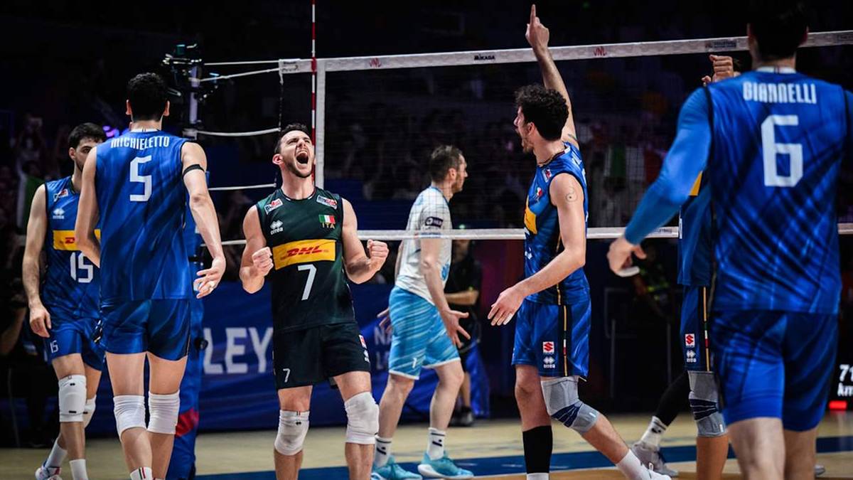 Siatkarze świętują zwycięstwo, niektórzy uniesieni emocjami, inni wskazują palcem w górę. W tle siatka do siatkówki i trybuny.