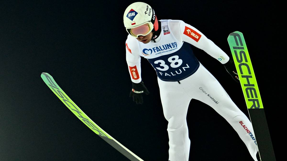 Skoczek narciarski w kombinezonie z numerem 38 i kasku z goglami podczas lotu na nartach.