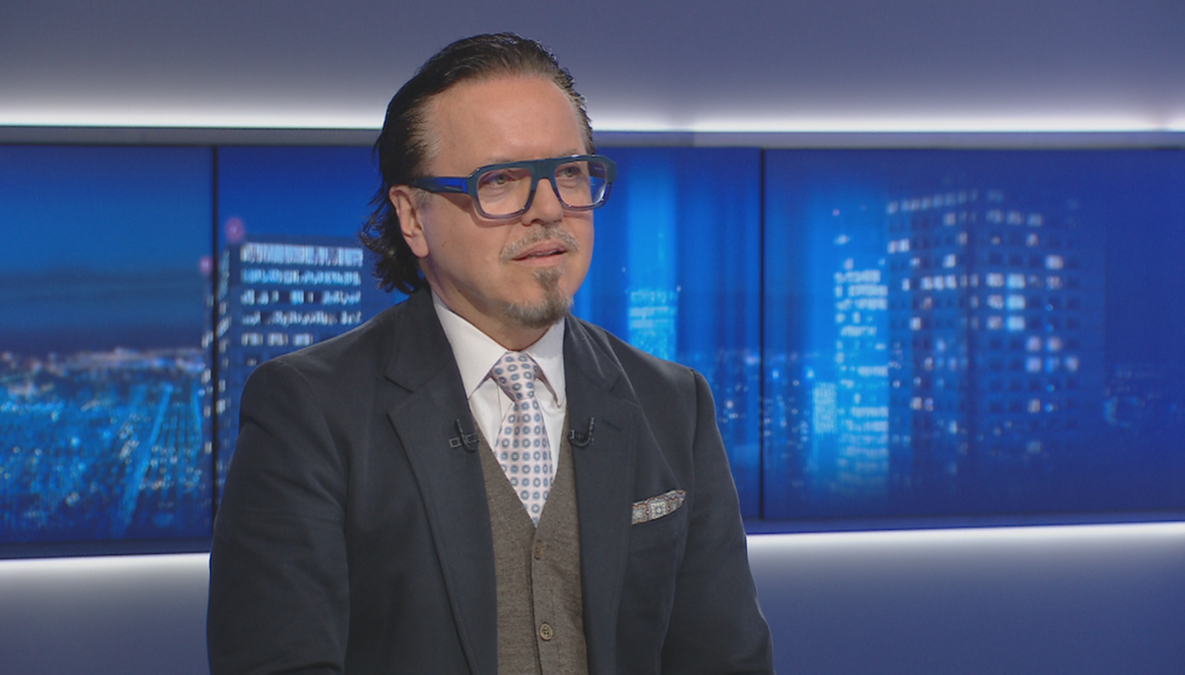 Minister aktyw&oacute;w państwowych Wojciech Balczun w okularach i garniturze siedzi w studiu telewizyjnym.