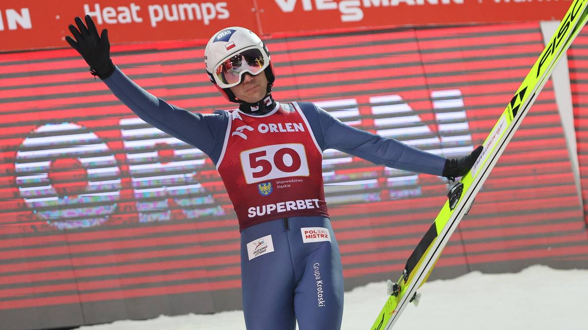 Skoczek narciarski Kamil Stoch w kombinezonie z numerem 50 unosi ręce w geście radości.