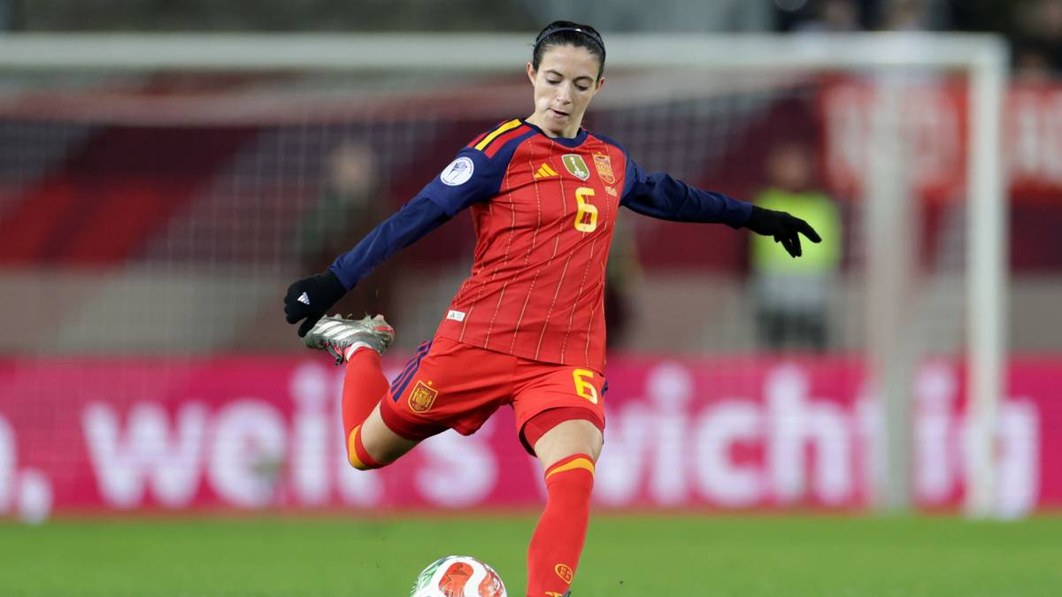 Piłkarka w czerwonym stroju wykonuje kopnięcie w piłkę nożną na boisku.