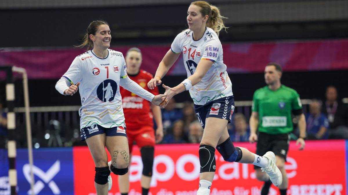 Dwie zawodniczki piłki ręcznej w białych strojach cieszą się po udanej akcji, podając sobie ręce.