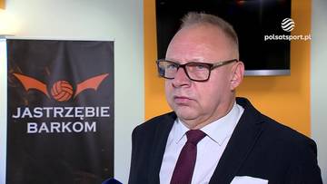 Adam Gorol w garniturze i okularach przed banerem z logo Jastrzębie Barkom