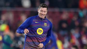 Piłkarz Robert Lewandowski w niebieskim stroju FC Barcelony biegnie po boisku, prowadząc piłkę.