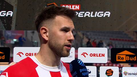 Kamil Adamski, zawodnik sportowy, udziela wywiadu na tle sponsor&oacute;w i logotyp&oacute;w sportowych.