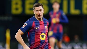 Dw&oacute;ch piłkarzy na boisku podczas meczu, jeden w ż&oacute;łtym stroju, drugi w stroju FC Barcelony.