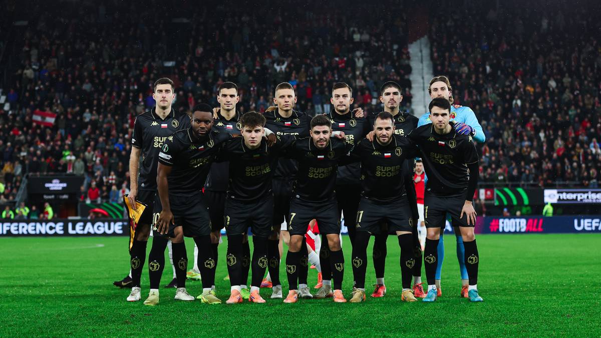 Drużyna piłkarska pozuje do zdjęcia na boisku piłkarskim.