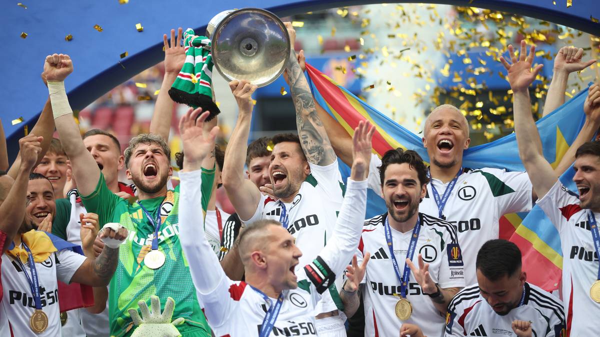 Piłkarze Legii Warszawa świętujący zwycięstwo w finale Pucharu Polski, unosząc trofeum i machając do publiczności wśród konfetti.