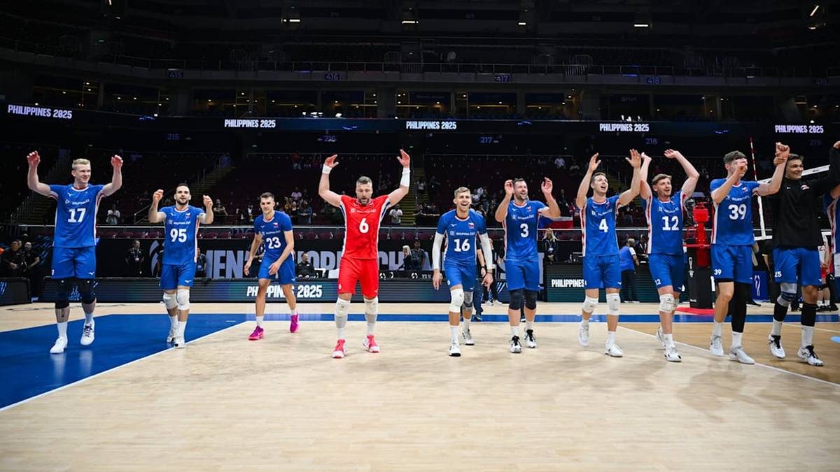 Drużyna siatkarzy w niebieskich strojach świętuje na parkiecie. Jeden zawodnik w czerwonym stroju stoi pośrodku z uniesionymi rękami.