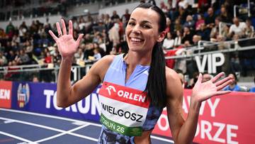 Uśmiechnięta lekkoatletka Anna Wielgosz pozuje do zdjęcia na bieżni, machając do kibic&oacute;w.