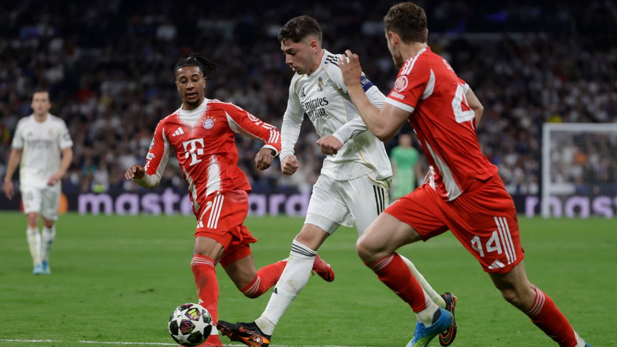 Trzech piłkarzy na boisku piłkarskim, dwóch w czerwonych strojach Bayernu Monachium walczy o piłkę z zawodnikiem w białym stroju Realu Madryt.