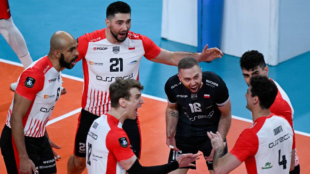 Siatkarze w strojach sportowych rozmawiają ze sobą na boisku podczas meczu.