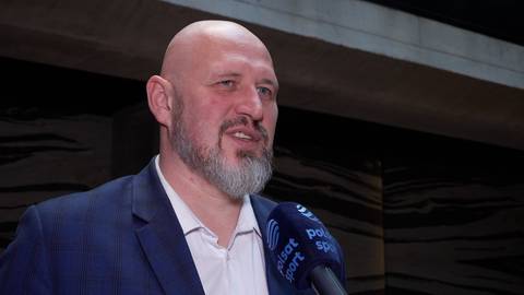 Tomasz Majewski, łysy mężczyzna z brodą, w garniturze, m&oacute;wi do mikrofonu z logo Polsat Sport.