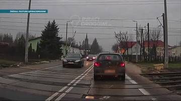 Rozpędzony pociąg zbliża się do przejazdu kolejowego, na którym szlabany są podniesione. Samochody stoją na torach, grożąc kolizją.