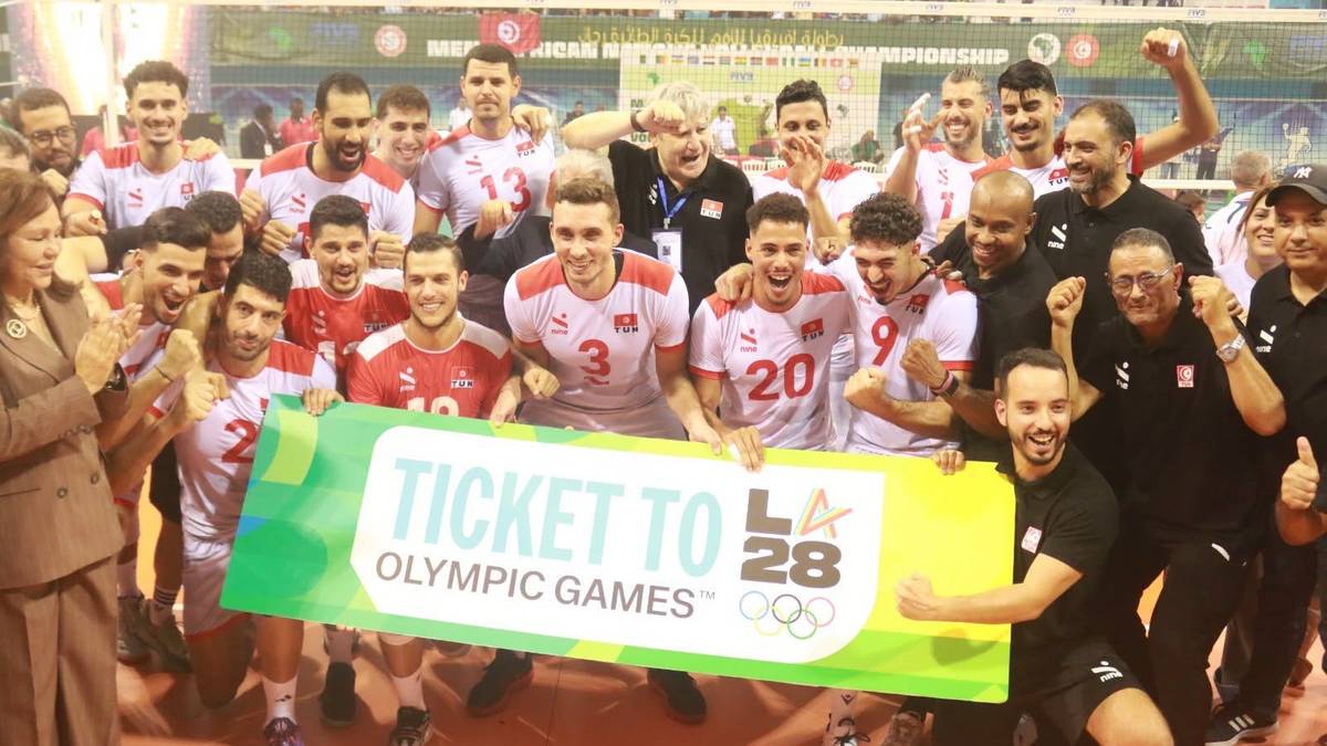 Siatkarze i członkowie sztabu radośnie pozują z zielonym banerem "Ticket to Olympic Games LA 28" po wywalczeniu awansu na igrzyska.