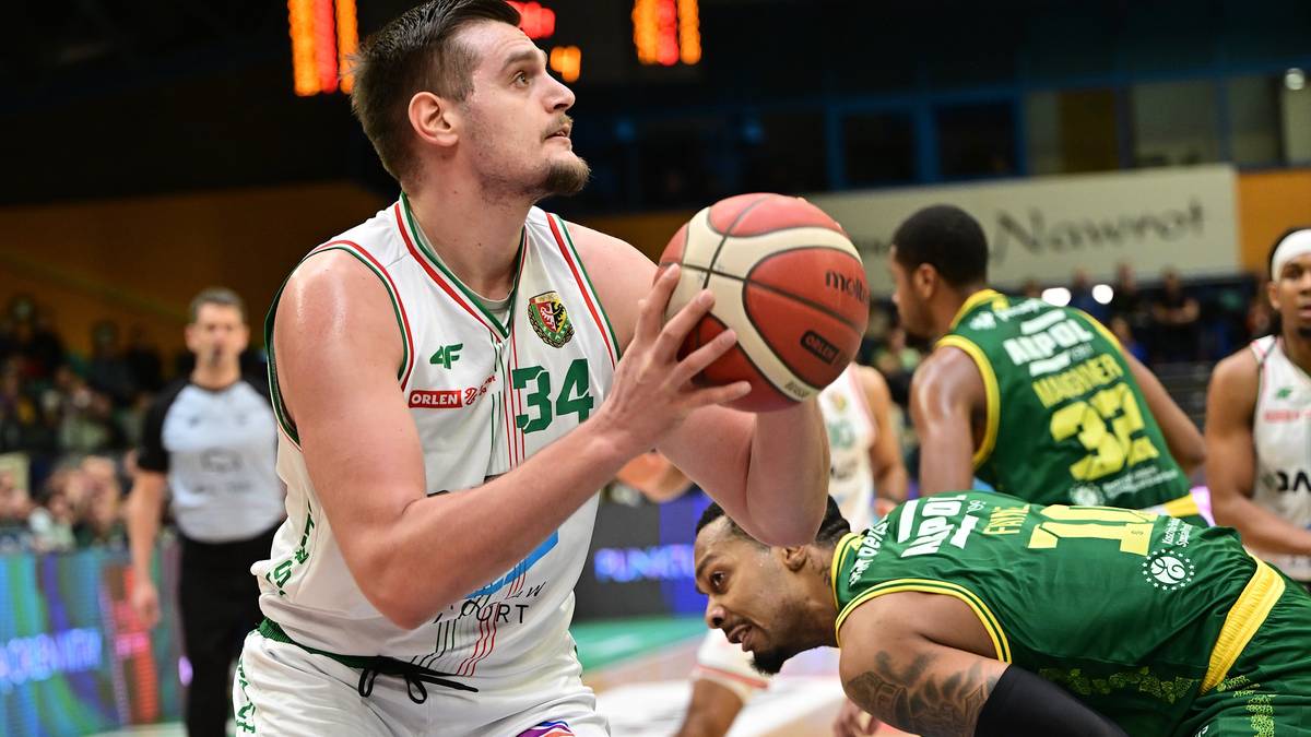 Koszykarz w białej koszulce z numerem 34 z piłką w rękach.