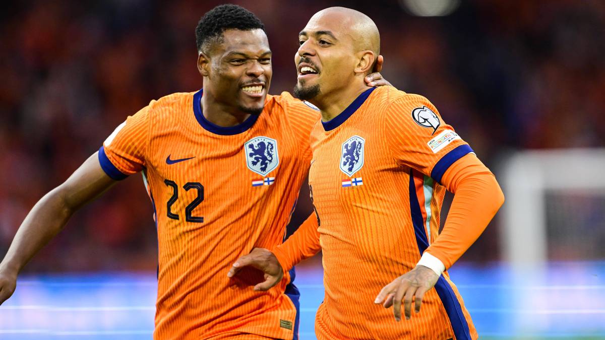 Dwóch piłkarzy reprezentacji Holandii w pomarańczowych koszulkach, jeden z nich ma numer 22 na plecach, obaj uśmiechają się do obiektywu.